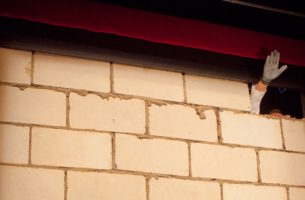 Hand waving through hole in brick wall